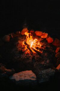 Warm campfire glowing in the dark, surrounded by rocks in a serene outdoor setting.